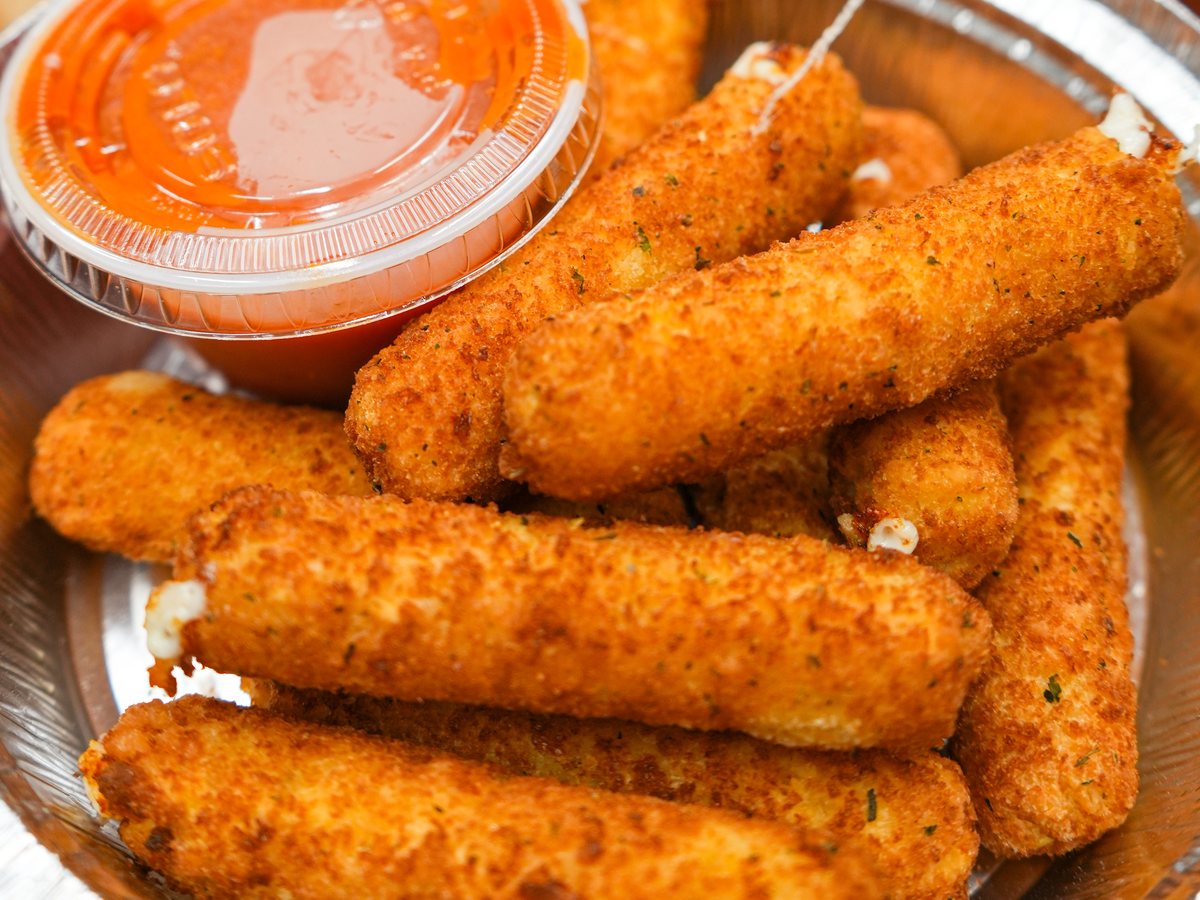 Golden fried mozzarella sticks with a cup of marinara